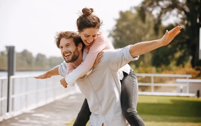 Glad man som bär sin partner på ryggen utomhus